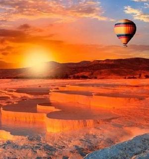 a hot air balloon flying over the desert at sunset