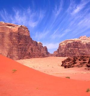 一辆汽车行驶在悬崖和红色沙子的沙漠中
