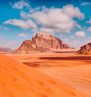 pouštní scéna s kameny a pískem v popředí