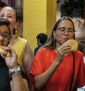 three women eating hot dogs at a table with food