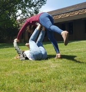 a woman standing on top of a person on the grass