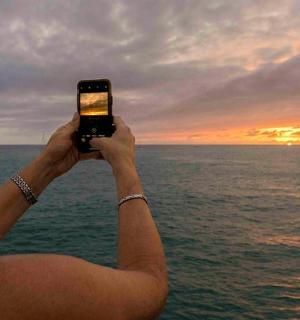 一位女士用手机拍摄大海