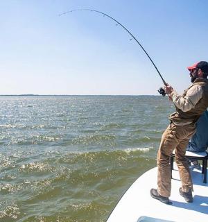 a man standing on a boat fishing on the water