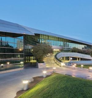 a large glass building with lights in front of it