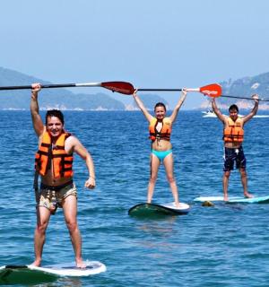 tři lidé stojí na paddleboardech ve vodě