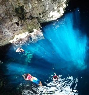 en gruppe mennesker, der svømmer i vandet nær en hule