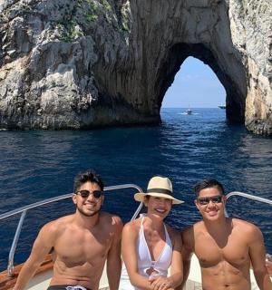 three men and a woman on a boat in front of a cave