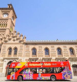 一辆红色巴士停在一座钟楼前的建筑物前