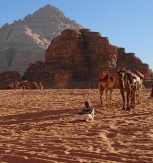 Skupina lidí a velbloud v poušti