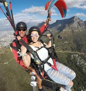 two people are riding a parachute on the mountain