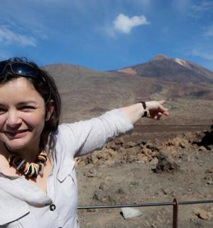 一名女子指着沙漠中的一座山