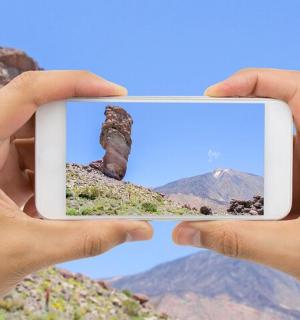 一个人用手机拍摄山峰