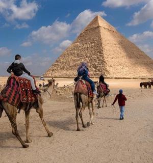 三个人骑着骆驼在金字塔前