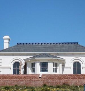 一栋白色的房子，前面有砖墙