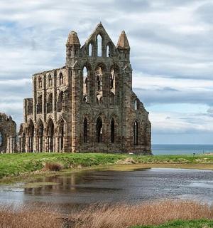 an old building on a field with a body of water