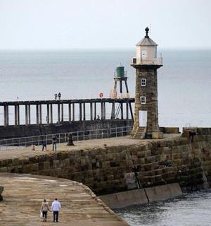 a lighthouse on a pier next to the ocean