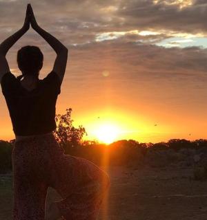 a woman doing a yoga pose in front of the sunset