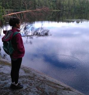 maður með bakpoka stendur við stöðuvatn