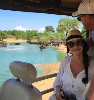 a man and a woman in a vehicle looking at a herd of elephants