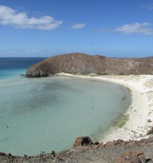 a beach with a large rock and the ocean