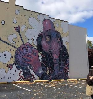 一名男子站在建筑物壁画前