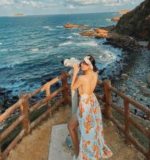 一位穿着裙子的女士正在拍摄大海