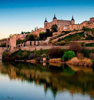 a castle on a hill next to a river with a bridge