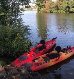 un kayak rosso appoggiato sulla riva di un fiume