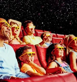 a group of people sitting in a theatre wearing sunglasses