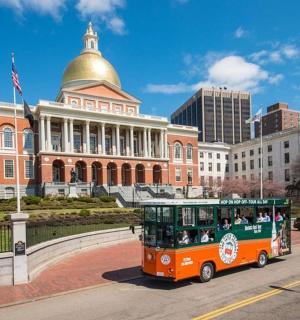 一辆橙色电车沿着建筑物前的街道行驶