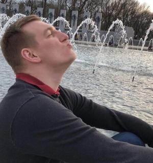 mladý muž sedící před fontánou