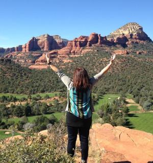 一位女士站在山顶上，双臂高举