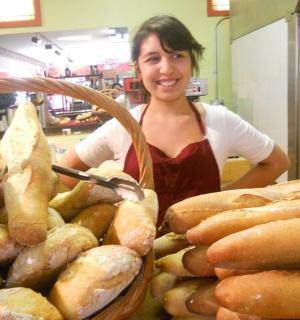 a woman in a bakery with a basket of bread