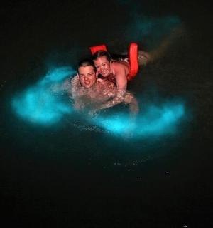 two men are swimming in the water at night