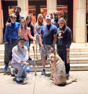 a group of people standing in front of a building with a dog