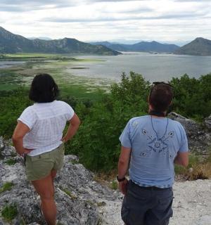 dva lidé stojící na skále a dívající se na jezero