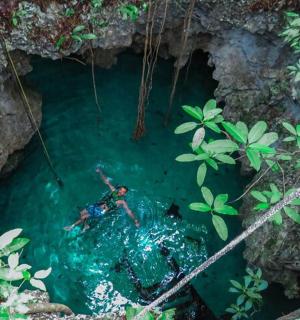 a person in a pool of water in a cave
