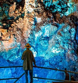 muž stojící na zábradlí a dívající se na modrou jeskyni