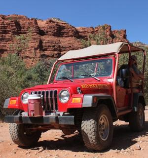 červený džíp jedoucí po nezpevněné cestě