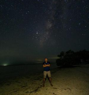 a man standing on a beach under a starry sky