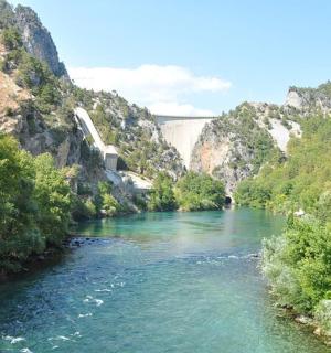 a river in a canyon with a bridge in the background