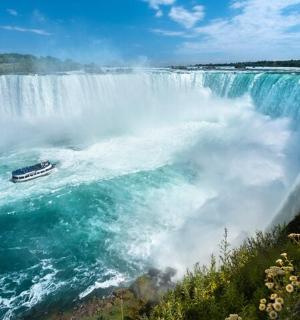 a boat in the water at the brink of a waterfall