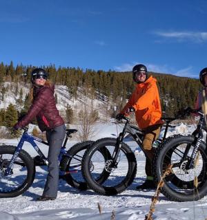 skupina tří lidí na kolech ve sněhu