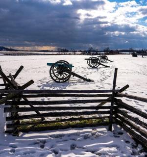 a fence in a snow covered field with two carts