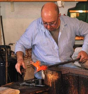 egy férfi egy darab fémet vág az asztalon