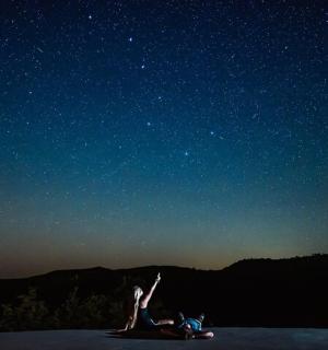 žena ležící na zemi pod hvězdnou oblohou