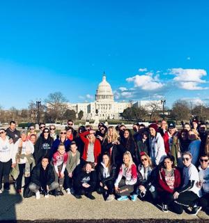 Skupina lidí pózuje před budovou Kapitolu