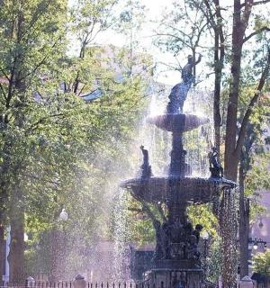 a fountain in a park with people standing around it