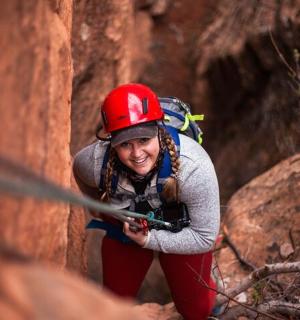 一名戴着红色头盔的女子正在攀爬悬崖