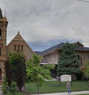 a building with a clock tower and a person walking in front of it